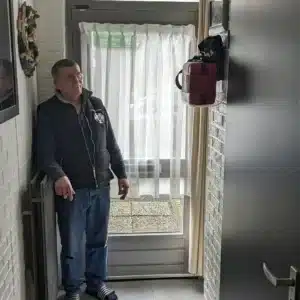 Man standing near a red AED case mounted in a hallway.